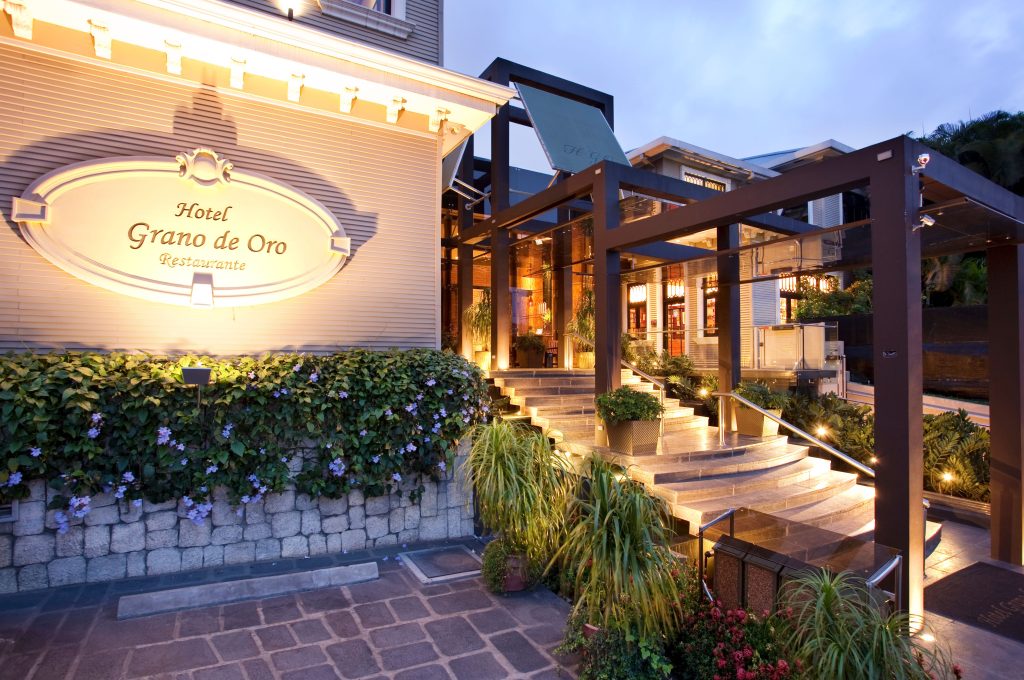 Hotel Grano de Oro" sign at the hotel entrance, surrounded by lush tropical plants and stone-lined pathways.
