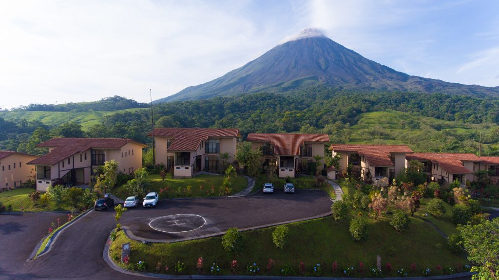 An aerial shot of the resort's guest suites and parking areas set against the backdrop of the verdant Costa Rican countryside and the volcano.