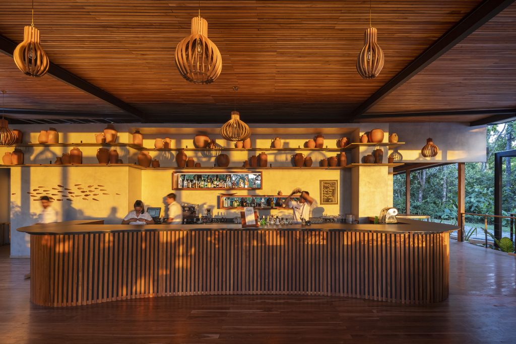 Rustic wooden bar and lounge area inside El Remanso Rainforest Lodge with high ceilings and sustainable design.
