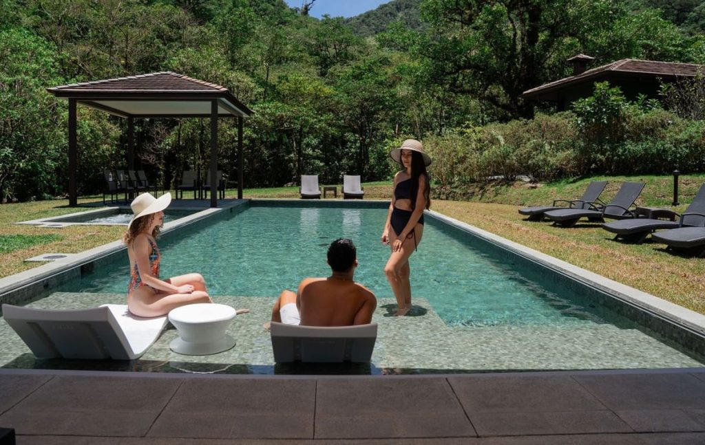 Guests relaxing by the infinity-edge swimming pool at El Silencio Lodge with views of the surrounding mountains.