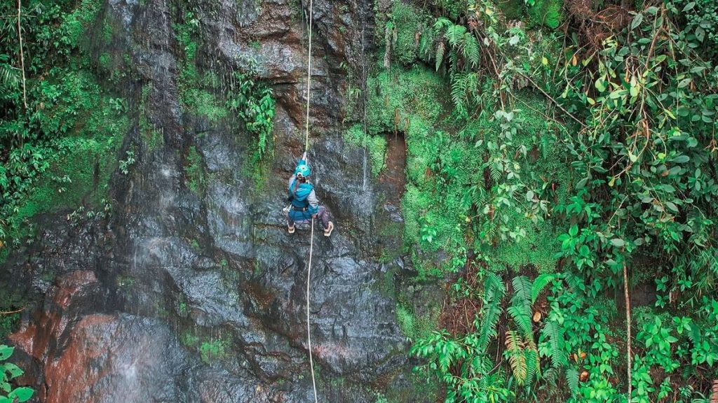 Adventurous traveler rappelling down a waterfall (canyoning) at El Silencio Lodge & Spa in Bajos del Toro.